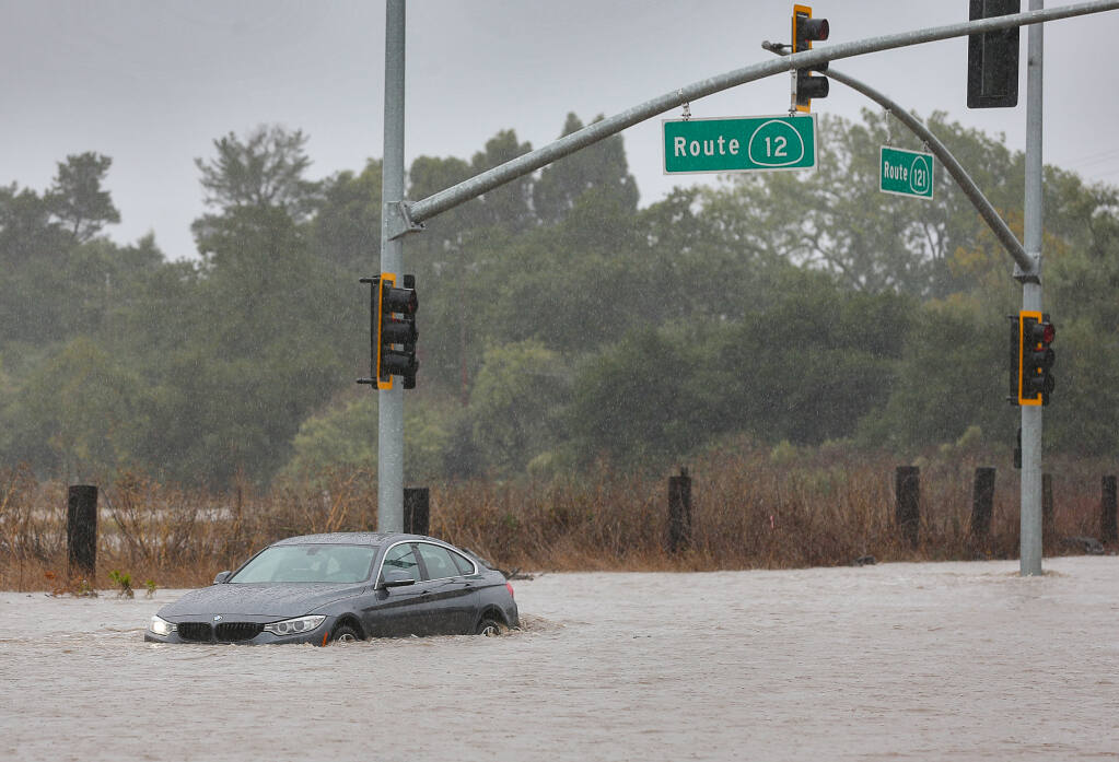 An abandoned vehicle sits in high water at the intersection of Highway 121 and Highway 12  in Schellville on Sunday, October 24, 2021.  (Christopher Chung/ The Press Democrat)