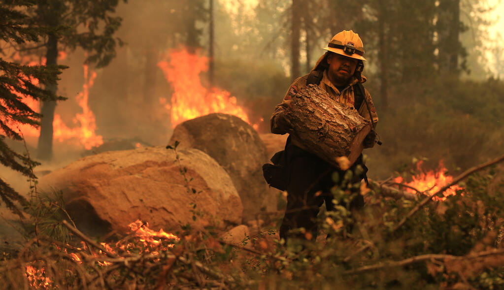 Cal Fire's Jose Vasquez clears out debris as the Caldor fire burns brush along Highway 50 in Meyers, Tuesday, Aug. 31, 2021.   (Kent Porter / The Press Democrat) 2021