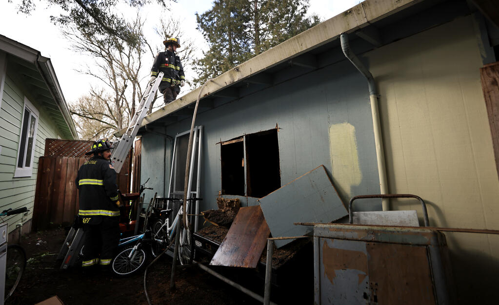 Gold Ridge  Fire Protection District firefighters prepare to look for any hot spots on the roof of a home along Highway 116 south of Sebastopol, Sunday, Jan. 30, 2023, where two people died in a house fire. (Kent Porter/The Press Democrat)