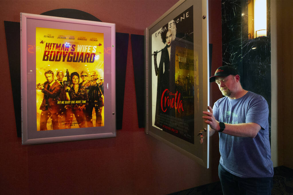 Brian Young, proprietor of Prime Cinemas, installs a new movie posters in a lobby light box on Tuesday, May 25, 2021. (Photo by Robbi Pengelly/Index-Tribune)