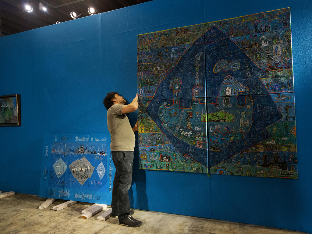 Preparator Raul Garcia adjusts one of the four canvases that makes up the ‘Bay of Bengal.’ The new SVMA show, ’Sacred Landscapes,’ presents works by Ynez Johnston. The exhibition starts on Saturday, June 12 and runs through Sept. 5, 2021.  {Photo by Robbi Pengelly/Index-Tribune)