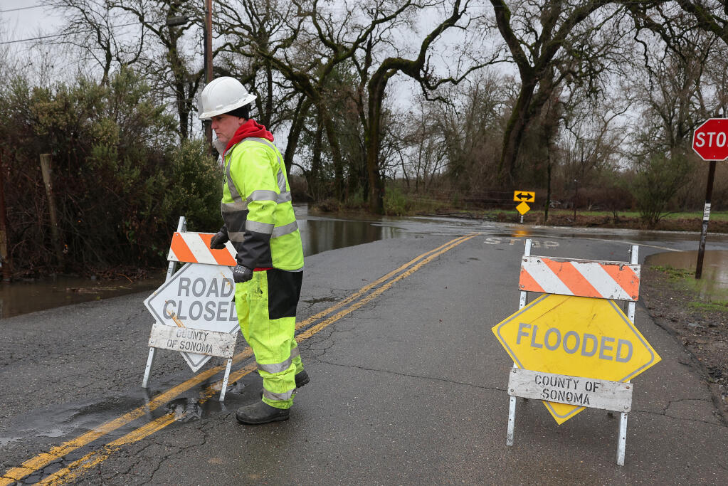 Cory Hayes, with Sonoma County Public Works, closes Starr Road at Mark West Station Road, near Windsor, due to flooding, Wednesday, Jan. 4, 2023. (Christopher Chung / The Press Democrat file)