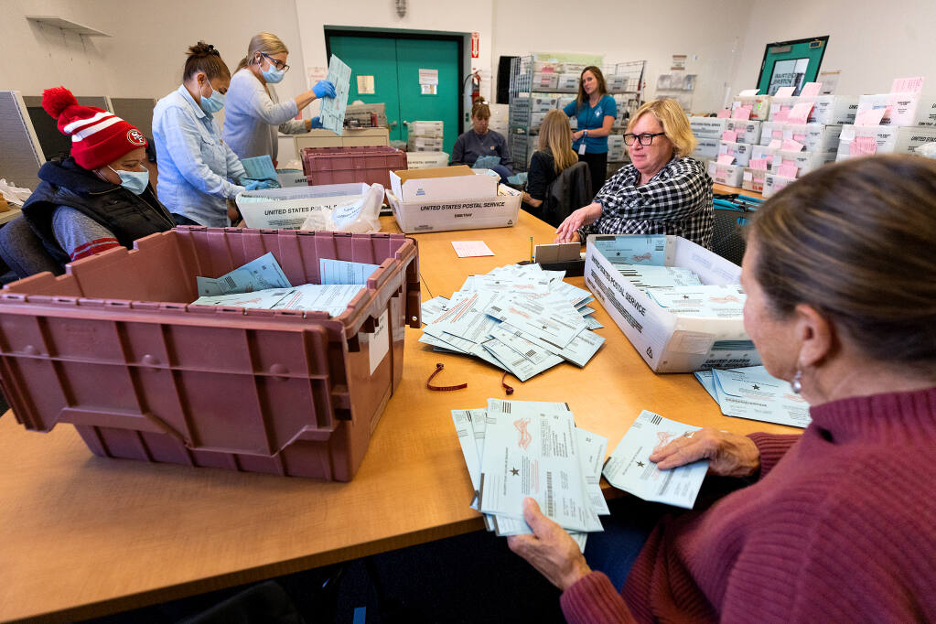 Staff must first take mail in ballots, dropped randomly into boxes, and stack them in the same orientation for a counting machine Wednesday, Nov. 9, 2022, at the Sonoma County Registrar of Voters office in Santa Rosa. (John Burgess / The Press Democrat)