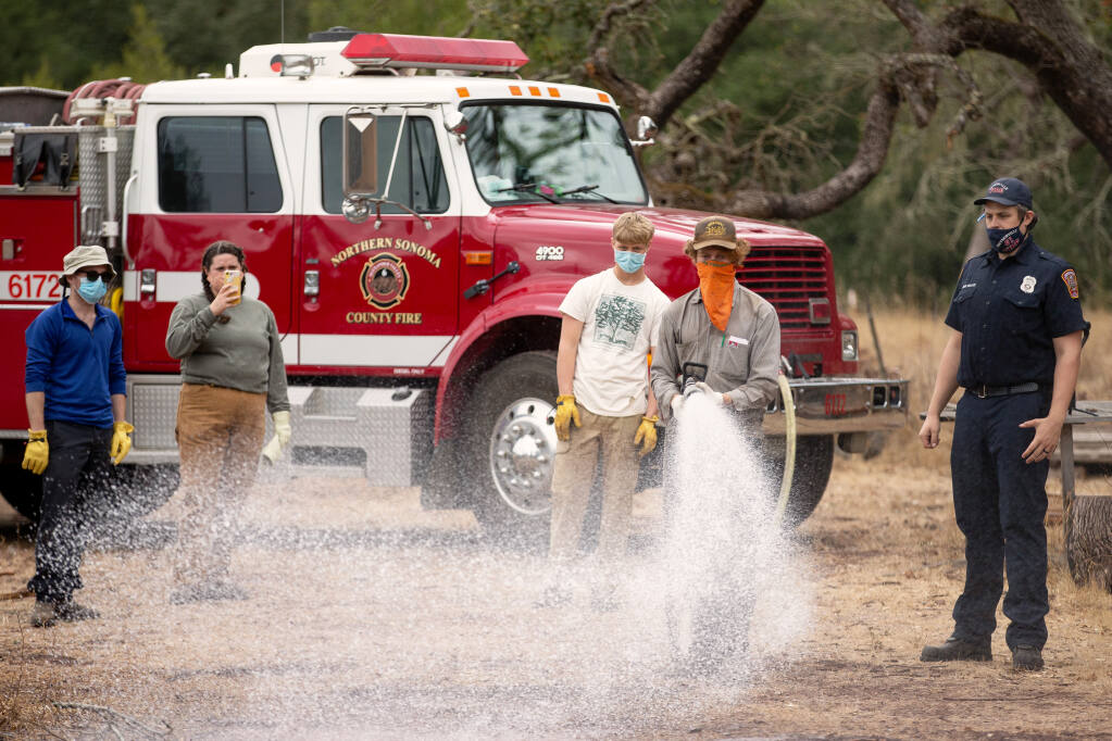 Volunteer Jake Olson sprays water from a fire engine bumper line as instructed by Northern Sonoma County Fire Protection District firefighter Andrew Wallace, at right, during basic wildland firefighting skills training by Audubon Canyon Ranch's Fire Forward program at Bouverie Preserve near Glen Ellen on Saturday, Oct. 10, 2020. (Alvin A.H. Jornada / The Press Democrat)