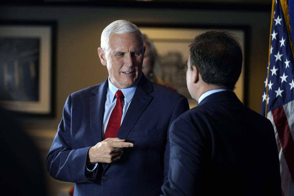 Former Vice President Mike Pence, left, greets people while signing copies of his book "So Help Me God" before the start of a GOP fundraising dinner, Thursday, March 16, 2023, in Keene, N.H. (AP Photo/Steven Senne)