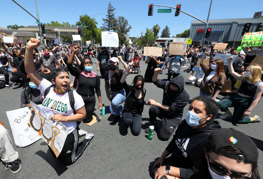 Protestors marching against police brutality kneel to block traffic at the intersection of Mendocino Avenue and Steele Lane, in Santa Rosa on Monday, June 1, 2020. The protestors blocked the intersection for nine minutes in honor of George Floyd.(Christopher Chung/ The Press Democrat)