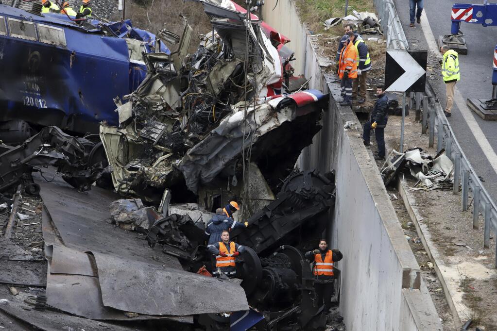 Workers supported by a crane try to remove debris from the rail lines after a collision in Tempe, about 376 kilometres (235 miles) north of Athens, near Larissa city, Greece, Thursday, March 2, 2023. Emergency workers are searching for survivors and bodies after a passenger train and a freight train crashed head-on in Tempe, central Greece just before midnight Tuesday. It was the country's deadliest rail crash on record. (AP Photo/Vaggelis Kousioras)