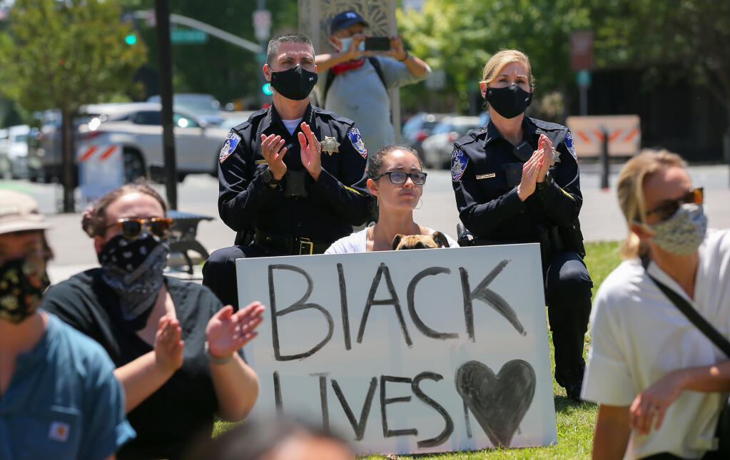 Santa Rosa Police Chief Ray Navarro, left, and Lt. Jeneane Kucker kneel with protesters in Old Courthouse Square, in Santa Rosa on Monday, June 1, 2020. (Christopher Chung/ The Press Democrat)