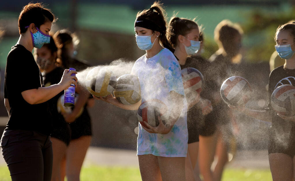 Windsor High School volleyball coach Christen Hamilton disinfects volleyballs to guard against the coronavirus as the Jaguars hold their practice outdoors in the school quad, Wednesday, Sept. 23, 2020. (Kent Porter / The Press Democrat)