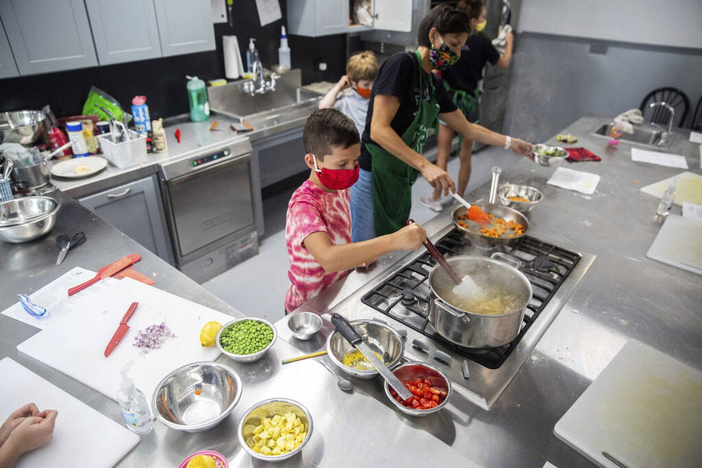 FILE - In this July 21, 2020, file photo, Cole Rossi, 8, keeps an eye on a pot of pasta during a Real Food 4 Kids cooking class taught by Sue Honkamp at Kitchen Spaces in Des Moines. Since August 2019, owner Bob Mulvihill has been renting Kitchen Spaces to entrepreneurs who are looking to start their small businesses without the huge capital investment needed to own or rent, remodel and staff a building.(Kelsey Kremer /The Des Moines Register via AP )