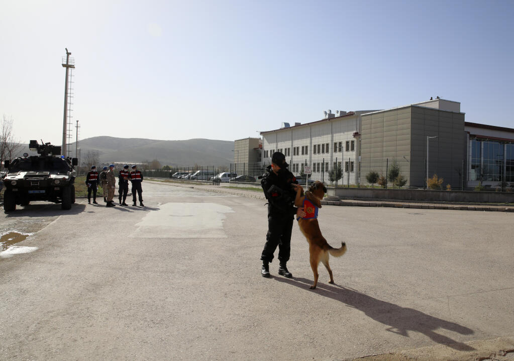 Bulent Okurcan, a military police officer stands with his 7-year-old Belgian wolf, Ihbar, as people wait outside a courthouse before the trial of 497 defendants, in Sincan, outside the capital Ankara, Turkey, Wednesday, April 7, 2021. The court was expected to deliver a verdict in their trial for involvement in a failed coup attempt in 2026. The court was expected to deliver a verdict in their trial for involvement in a failed coup attempt in 2026.(AP Photo/Burhan Ozbilici)