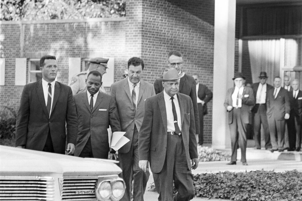 James Meredith manages a grin while returning to car with marshals in Oxford, Miss., on Sept. 20, 1962 after Gov. Ross Barnett turned his application down as the first African American to attend the University of Mississippi. The tall man behind the sheriff in the cowboy hat is Assistant U.S. Atty. Gen. St. John Barrett. (AP Photo/Fred Waters)