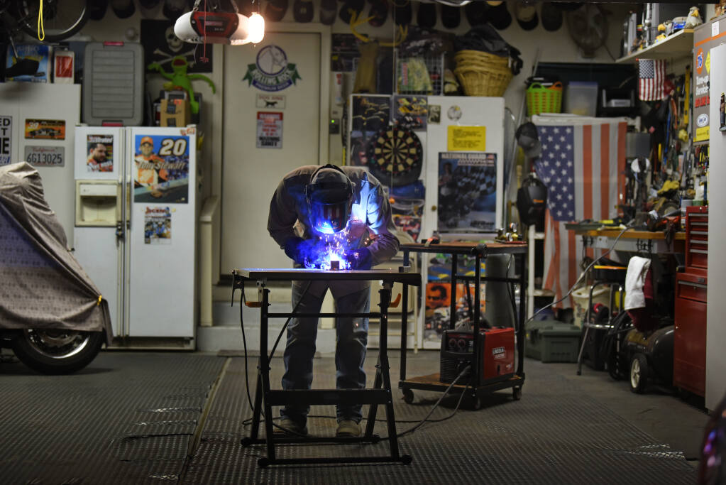 Petaluma High School junior Adam Jason, 16, welding in his garage at his home in Petaluma on Thursday, Feb. 18, 2021. Adam first took a welding class last year at his high school and has been working as a welder during the entire pandemic at Wine Country Ranch Equipment in Cotati doing four-hour shifts every weekday. (Erik Castro / For The Press Democrat)