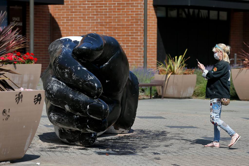 Shellee Harper-Post snaps photographs of the "hand" outside Santa Rosa Plaza after the 7.5 ton white marble sculpture was painted black in apparent solidarity with the Black Lives Matter movement, in Santa Rosa, California, on Saturday, Aug. 1, 2020. (Alvin A.H. Jornada / The Press Democrat)