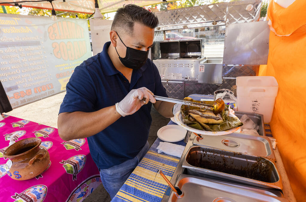 Neil Pacheco prepares a chicken mole tamale topped with crema, salsa, queso, micro greens and sprinkle of mole salt at his stand in the Roseland center, Tamales Oaxaqueños.  (John Burgess / The Press Democrat)