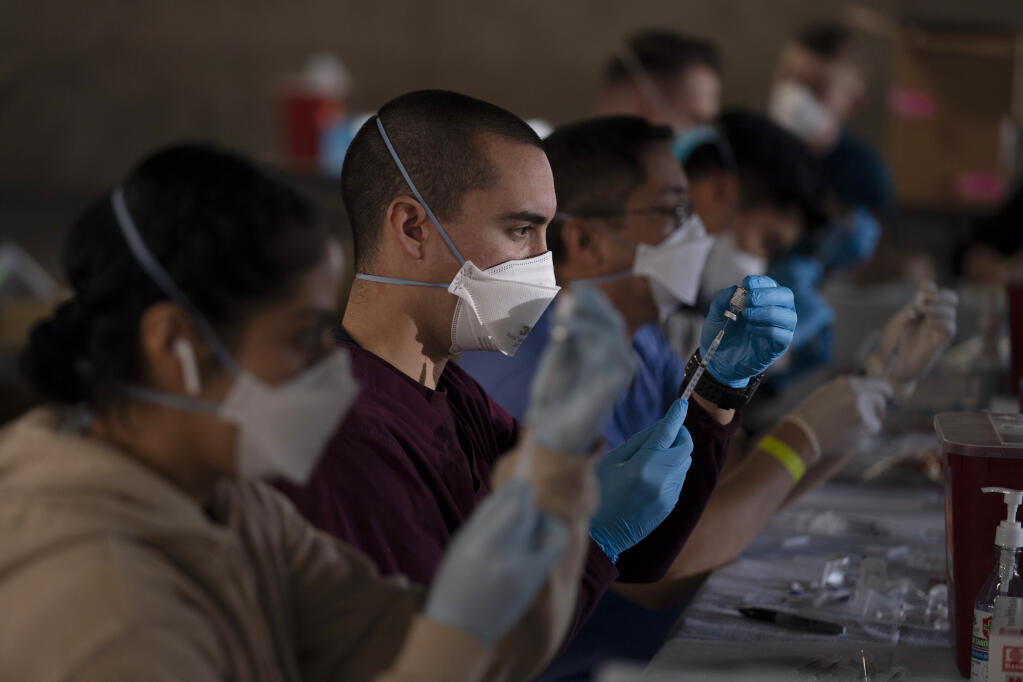 Members of the National Guard fill syringes with Pfizer's COVID-19 vaccine at a vaccination site in Long Beach, Calif., Friday, March 5, 2021.  (AP Photo/Jae C. Hong)