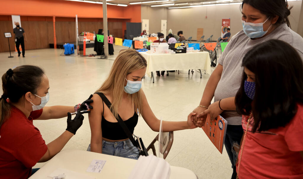 Finally convinced by a group of her friends that the COVID-19 vaccine shot wouldn't hurt, Araceli Virrueta,17, receives comfort from Miriam Solario, 16, middle, and Fatima Arrevelo, 10.  Giving the vaccine is Jodi Anne of Santa Rosa Community Health, Saturday, July 31, 2021    (Kent Porter / The Press Democrat) 2021
