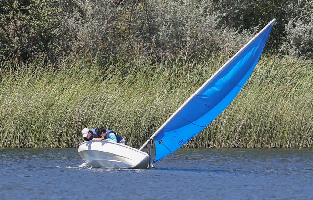 Mitchell Patterson, left, 12, and and Beckett Teich, 11, look at the bottom of their boat while allowing it to lean with the wind during the Sailing Camp for Youth at Lake Ralphine in Howarth Park in Santa Rosa on Monday, July 11, 2022.  (Christopher Chung / The Press Democrat)