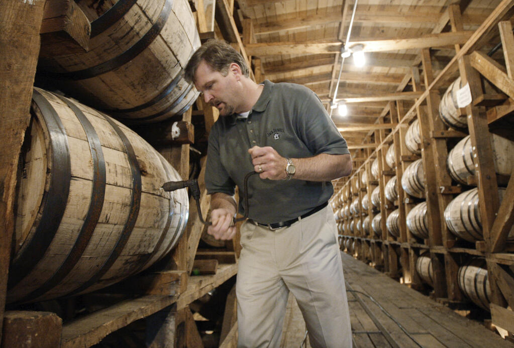 FILE – In this May 20, 2009, file photo, Jeff Arnett, the master distiller at the Jack Daniel Distillery in Lynchburg, Tenn., drills a hole in a barrel of whiskey in one of the aging houses at the distillery. (AP Photo/Mark Humphrey, File)
