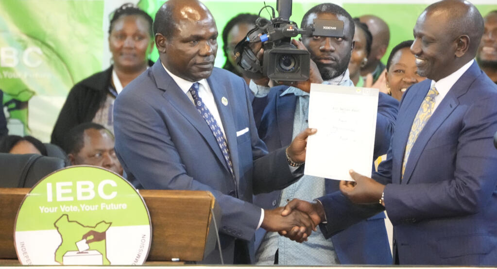 The Independent and Electoral Boundaries Commission (IEBC) Chairman, Wafula Chebukati, left, presents a certificate to William Ruto, after the announcement of the results of the presidential race at the Centre in Bomas, Nairobi, Kenya, Monday, Aug. 15, 2022. Kenya’s electoral commission chairman has declared Deputy President William Ruto the winner of the close presidential election over five-time contender Raila Odinga, a triumph for the man who shook up politics by appealing to struggling Kenyans on economic terms and not on traditional ethnic ones. (AP Photo/Sayyid Abdul Azim)
