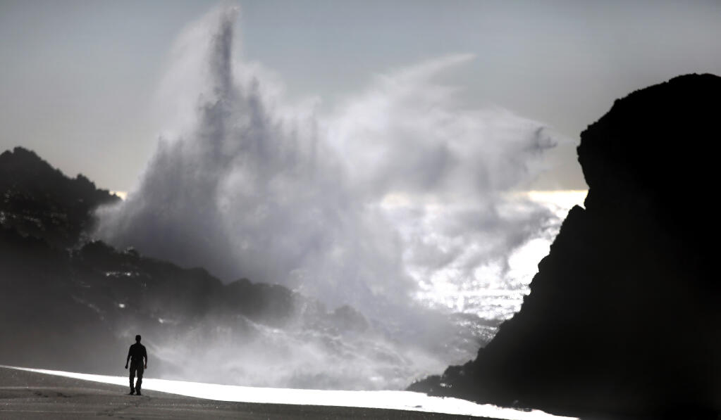 A visitor to Wright's Beach watches as a sneaker wave crashes in to Duncan's Landing, Monday, Dec. 7, 2020, north of Bodega Bay. (Kent Porter / The Press Democrat)