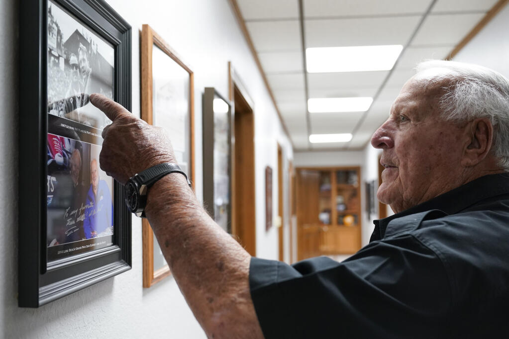 A.J. Foyt points to a 1967 photograph of him and fellow racing driver Dan Gurney at his office, Wednesday, March 29, 2023, in Waller, Texas. (AP Photo/Godofredo A. Vásquez)