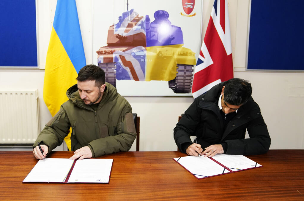 Ukrainian President Volodymyr Zelensky, left, and British Prime Minister Rishi Sunak sign a declaration of unity at a military facility in Lulworth, Dorset, England, Wednesday Feb. 8, 2023. (Andrew Matthews / POOL)