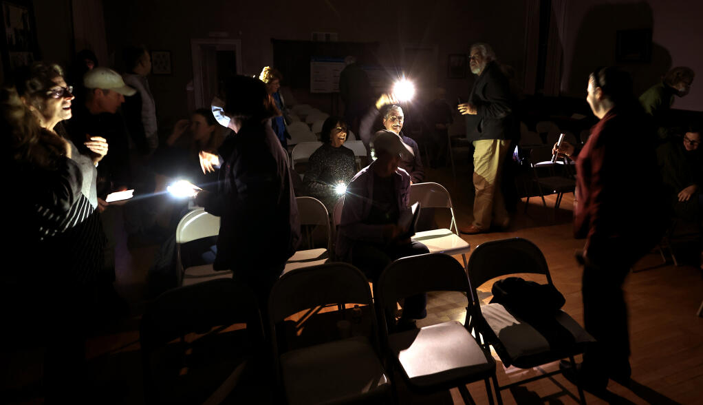 Bennett Valley residents use their wireless devices to illuminate the Bennett Valley Grange Hall, Tuesday, Jan. 24, 2023, after the power went out, near the end of a two-hour town hall meeting with representatives of Pacific Gas and Electric, to discuss the chronic power outages in the community. (Kent Porter/The Press Democrat)