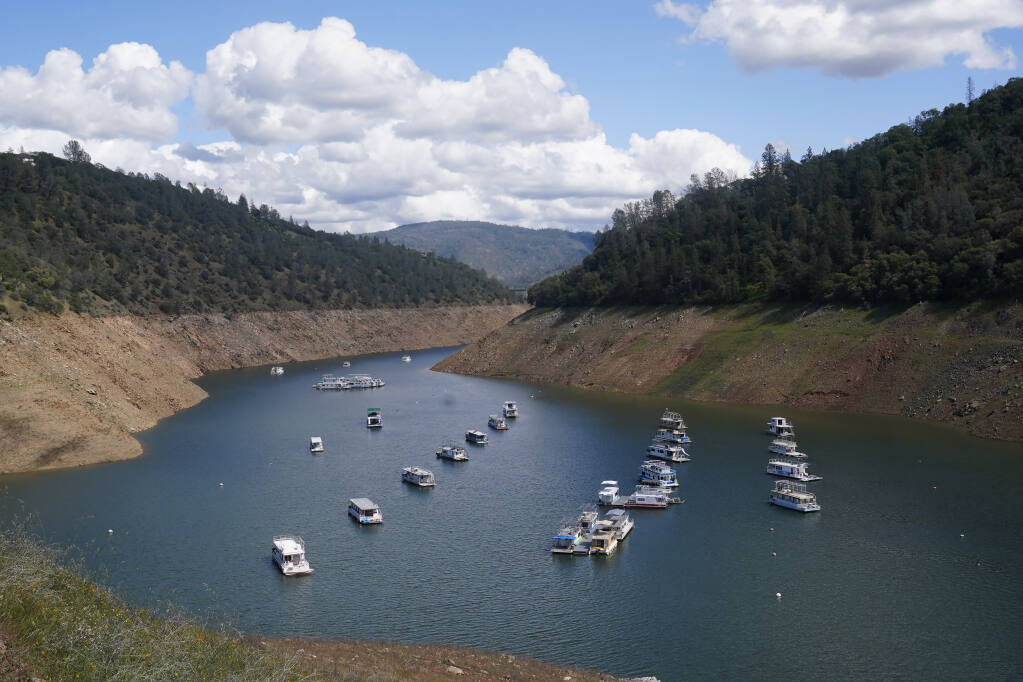 Houseboats sit in the drought lowered waters of Oroville Lake, near Oroville, Calif., Tuesday, April 19, 2022. (AP Photo/Rich Pedroncelli)