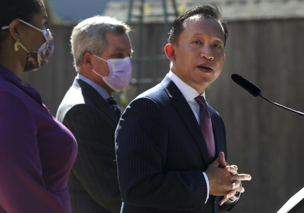 San Francisco City Attorney David Chiu, right, stands next to Mayor London Breed, left, and former City Attorney Dennis Herrera as he speaks during a press conference on Wednesday, Sept. 29, 2021 in San Francisco, Calif. Chiu has issued subpoenas seeking records from an unauthorized COVID-19 test operator and laboratory suspected of offering free testing in the city as the fast-spreading omicron variant drove up demand for testing. Chiu said "We cannot allow rogue actors to exploit this omicron surge for profit," (Lea Suzuki/San Francisco Chronicle via AP)