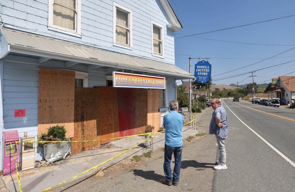 Rick Madson, right, who runs Seagull Antiques, and Brian Cluer talk about the vehicle that drove into the Bodega Country Store in Bodega on Monday, Aug. 30, 2021. The accident occurred late Saturday night.  (Christopher Chung/ The Press Democrat)