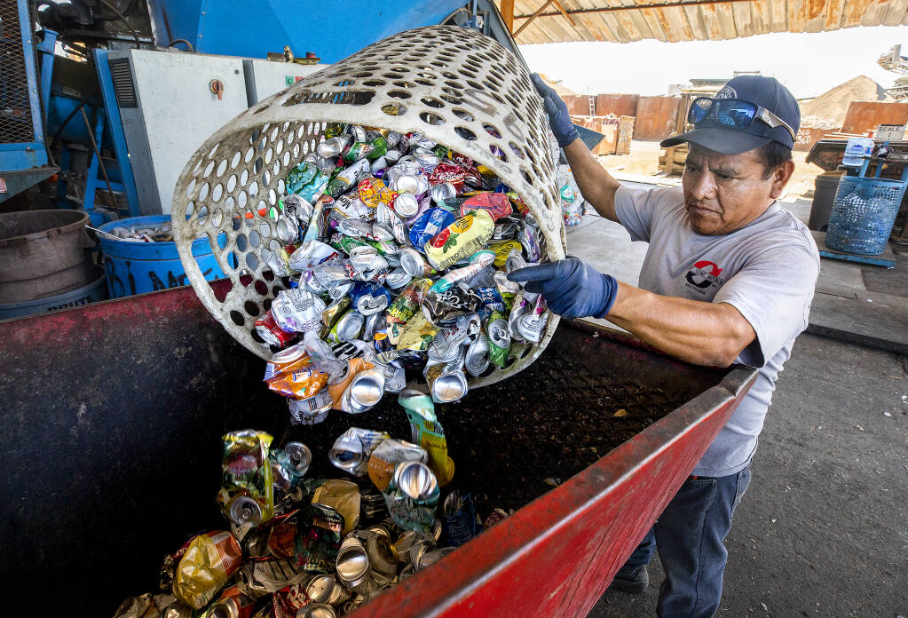 California Refund Value recycling center employee Julian Lopez empties bins of cans onto a conveyer leading to a truck at West Coast Metals in Windsor Friday, Aug. 12, 2022. (John Burgess/The Press Democrat)