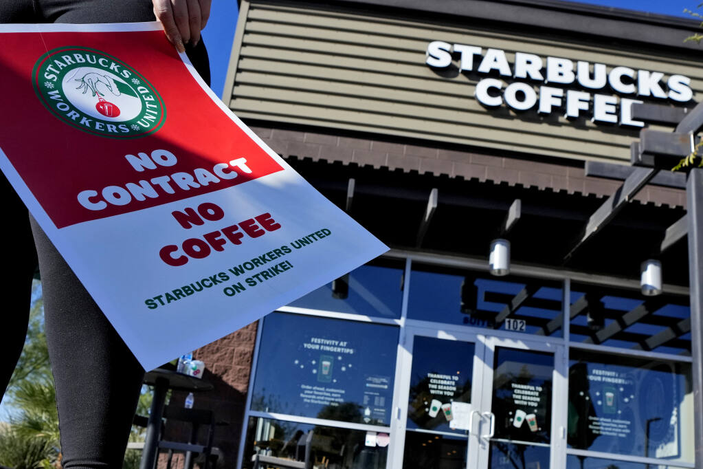 Starbucks employees strike outside their store Nov. 17 in Mesa, Ariz. More than 100 stores nationwide were striking with workers seeking better pay, more consistent schedules and higher staffing levels in busy stores according to Starbucks Workers United. (AP Photo/Matt York)