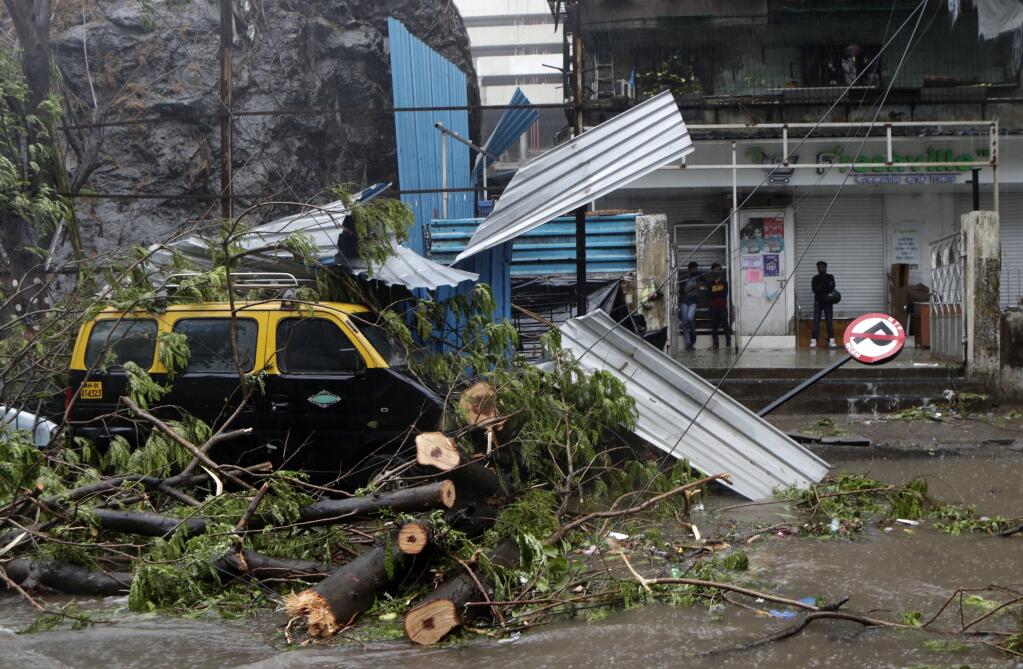 A taxi car that was damaged after a tree fell on it during a heavy rain in Mumbai, India, Monday, May 17, 2021.  Cyclone Tauktae, roaring in the Arabian Sea was moving toward India's western coast on Monday as authorities tried to evacuate hundreds of thousands of people and suspended COVID-19 vaccinations in one state. (AP Photo/Rajanish Kakade)