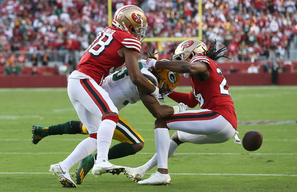 San Francisco 49ers defenders Deommodore Lenoir, left, and Josh Norman hit Green Bay Packers' Aaron Jones to force the ball loose during their game in Santa Clara on Sunday, September 26, 2021.  (Christopher Chung/ The Press Democrat)