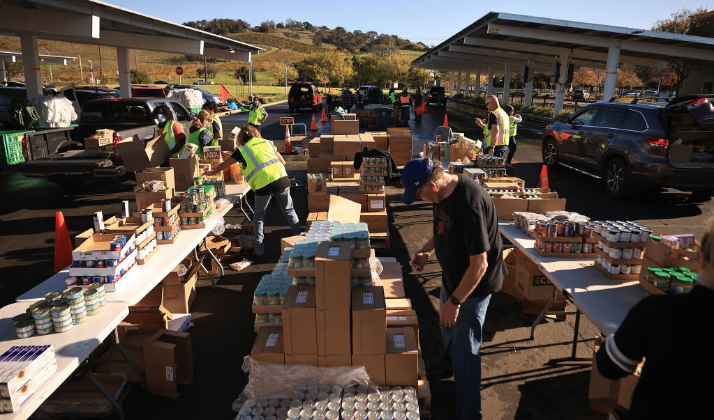 Volunteers with the Redwood Empire Food Bank pack groceries Nov. 20, 2021 during a food distribution giveaway in the parking lot at Kaiser Permanente's Old Redwood Highway location in Santa Rosa.  (Kent Porter / The Press Democrat) 2021