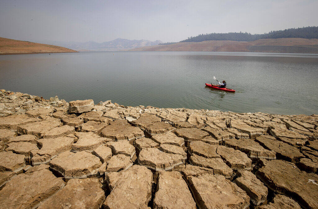 FILE - In this Aug. 22, 2021, file photo a kayaker fishes in Lake Oroville as water levels remain low due to continuing drought conditions in Oroville, Calif. California's reservoirs are so low from a historic drought that regulators warned Thursday, Sept. 30, 2021, it's possible the state's water agencies could get nothing from them next year, a frightening possibility that could force mandatory restrictions for residents. (AP Photo/Ethan Swope, File)