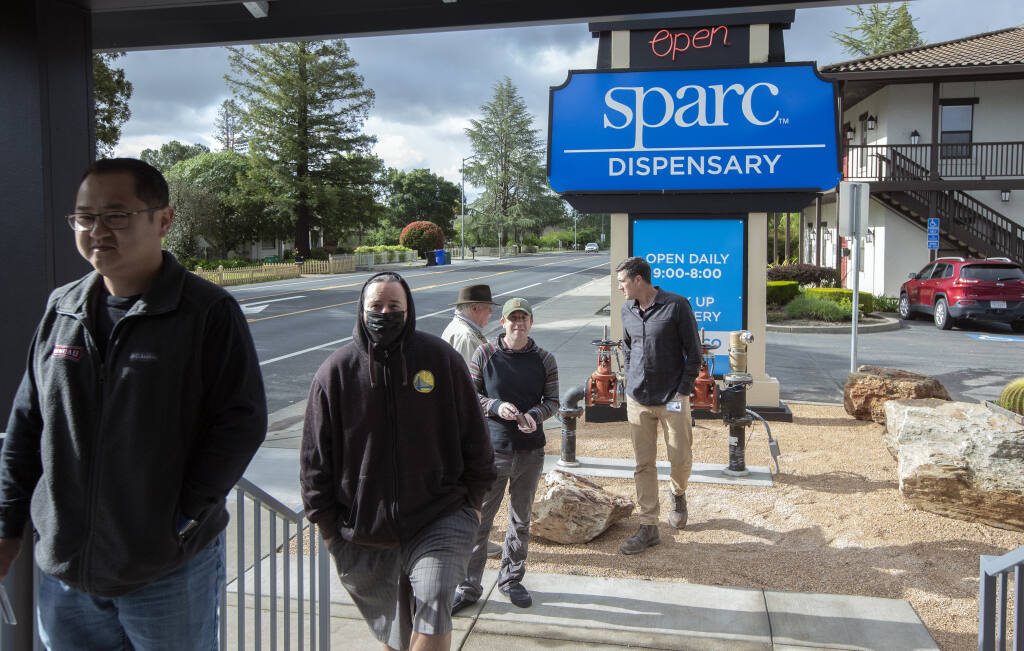 Eric Pearson, center, founder and CEO of SPARC, the first cannabis dispensary to open within the City limits, greeted his first customers on Wednesday, April 20, 2022. (Robbi Pengelly/Index-Tribune)