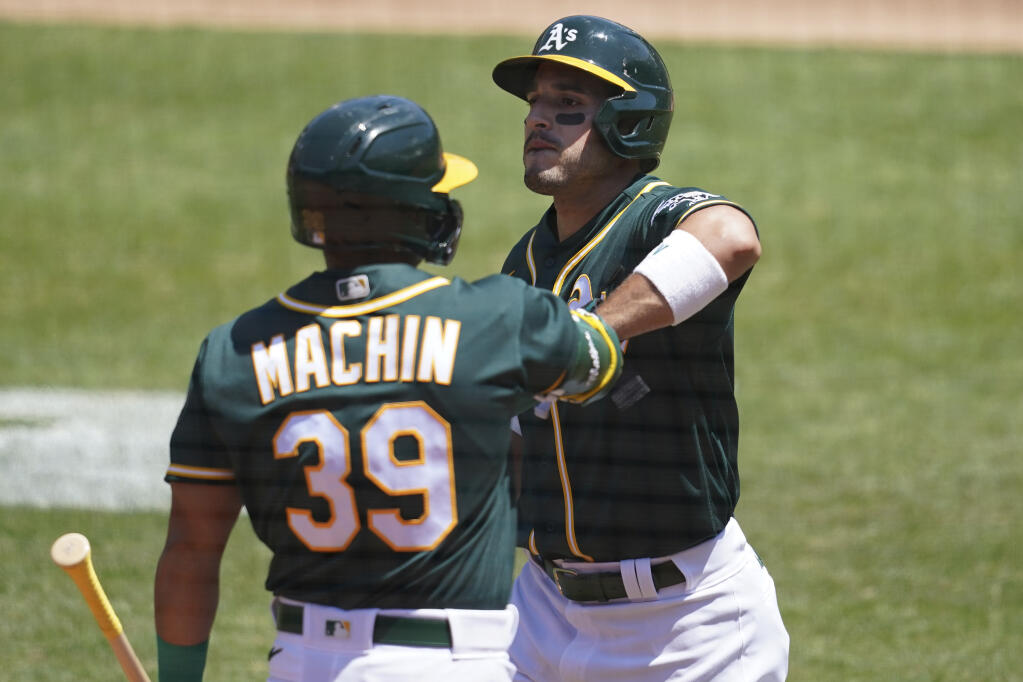 Oakland Athletics' Ramon Laureano, right, is congratulated by Vimael Machin after scoring against the Los Angeles Angels during the first inning of a baseball game in Oakland, Calif., Sunday, July 26, 2020. (AP Photo/Jeff Chiu)