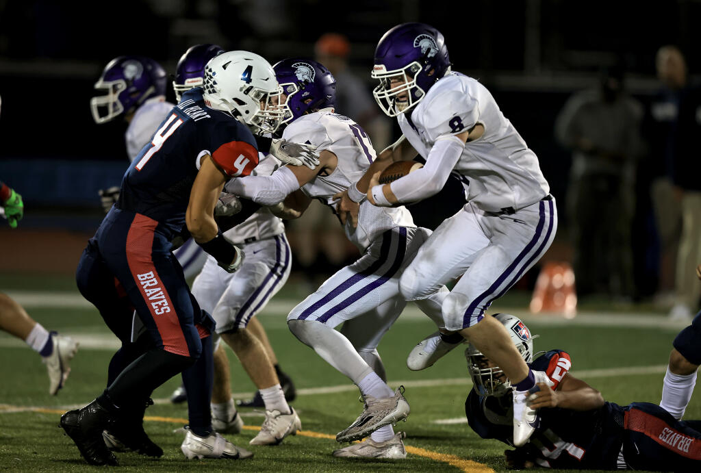 Petaluma quarterback Henry Ellis, right, breaks a fingertip tackle by Justin-Siena’s Gianni Natuzzi on Friday, Sept. 24, 2021 in Napa. Coming in for the tackle at left is Justin-Siena’s Cole Chatagnier. (Kent Porter / The Press Democrat)