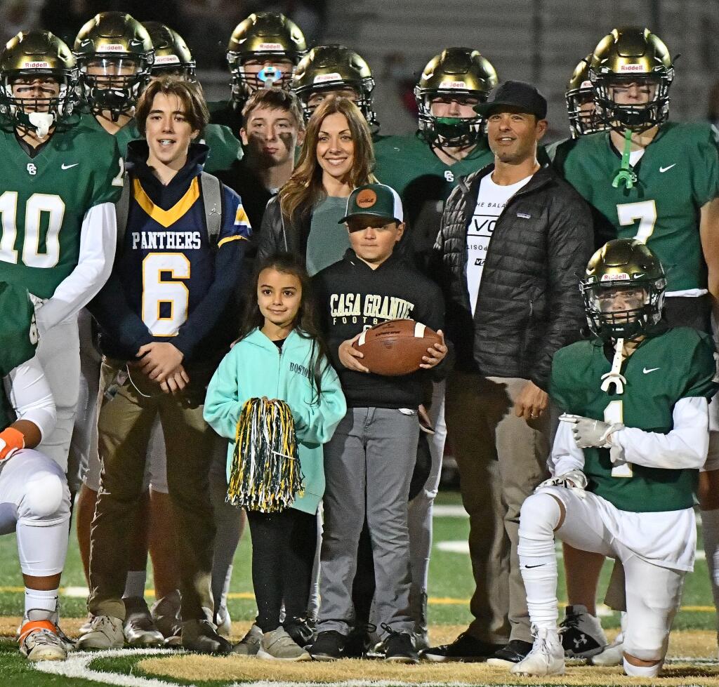 Jaden Cerda (with the ball) and his family - sisterJoya (front) brother Joey, mother Jihan and father Joe - are joined by the Casa Grande High School football team on the night a recovered Jaden served as team ball boy. (SUMNER FOWLER/FOR THE ARGUS-COURIER)