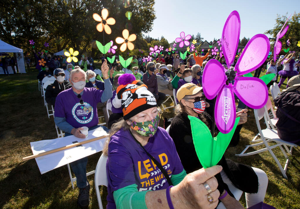 Ruth Grogan, of Santa Rosa, front, holds a flower symbolic of having lost someone to Alzheimer's, during the Sonoma-Marin Walk to End Alzheimer's at Sonoma State University in Rohnert Park, on Saturday, October 9, 2021. (Photo by Darryl Bush / For The Press Democrat)