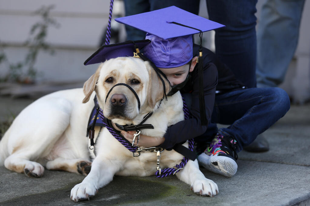 Max Stiles, 5, hugs his service dog Casper after a surprise graduation ceremony from the Paws As Loving Support (PALS) Assistance Dogs program outside his home in Santa Rosa, California, on Sunday, Jan. 17, 2021. (Beth Schlanker / The Press Democrat)