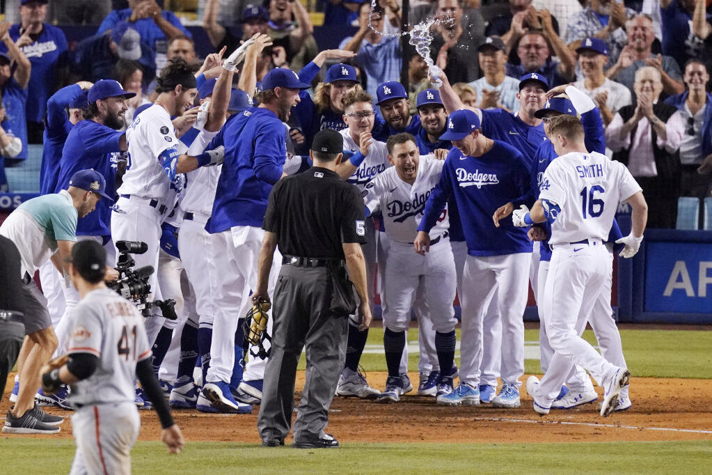 Members of the Los Angeles Dodgers celebrate as Will Smith, right, scores after hitting a three-run walk off home run during the ninth inning against the San Francisco Giants on Tuesday, July 20, 2021, in Los Angeles. (Mark J. Terrill / ASSOCIATED PRESS)
