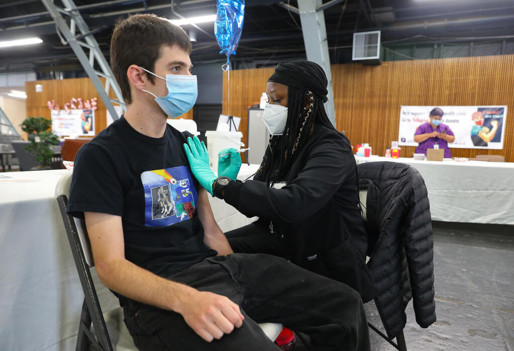 Nurse Miracle Huffman, right administers a leftover dose of Pfizer COVID-19 vaccine to Luke Herbert at the end of the day at the Sonoma County Medical Association vaccination clinic, at the Sonoma County Fairgrounds, in Santa Rosa on Friday, April 23, 2021.  (Christopher Chung/ The Press Democrat)