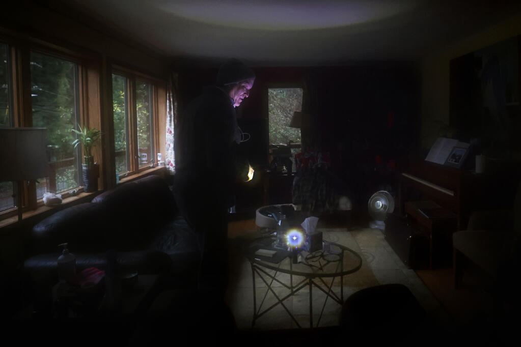 Villa Grande resident Tim Cahn, illuminated by his flashlight, has been living without power for a week. Photo taken at his home near Monte Rio, Calif., Tuesday, January 10, 2023. (Beth Schlanker/The Press Democrat)
