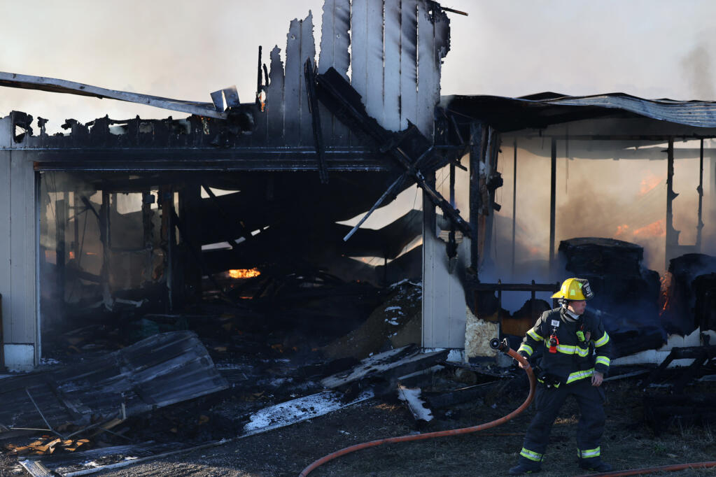 A Rancho Adobe firefighter works to extinguish a blaze at Protein Products LLC, a farm producing fly larvae for animal feed, in Petaluma, Sunday, Oct. 29, 2023. (Beth Schlanker / The Press Democrat)