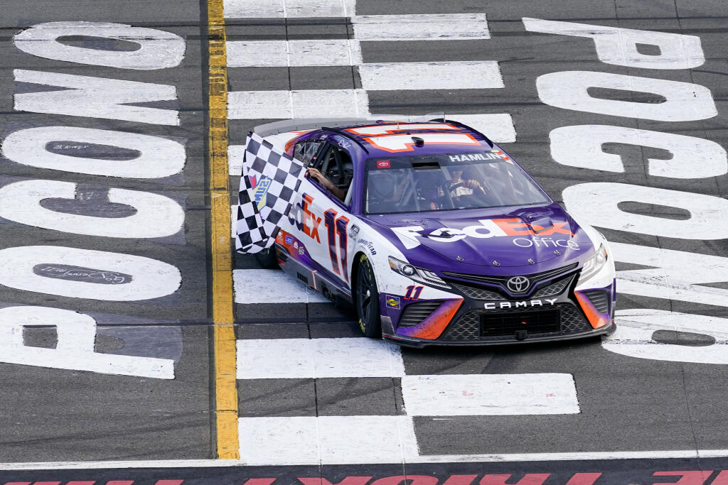 ADDS THAT HAMLIN WAS LATER DISQUALIFIED - Taylor James Hamlin, left, waves the checkered flag from inside the car with her dad, Denny Hamlin, after he won a NASCAR Cup Series auto race at Pocono Raceway, Sunday, July 24, 2022, in Long Pond, Pa. (AP Photo/Matt Slocum)