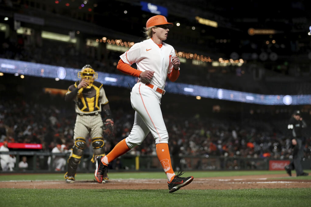 San Francisco Giants first base coach Alyssa Nakken runs to get in position near San Diego Padres catcher Austin Nola, left, during the third inning of a baseball game in San Francisco, Tuesday, April 12, 2022. (AP Photo/Jed Jacobsohn)