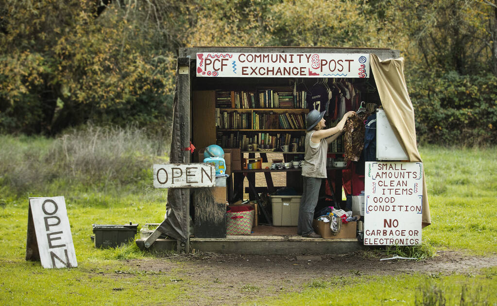 A visitor to the Pocket Canyon Farm Community Post Exchange looks through used clothing left by other visitors to the shack along Hwy. 116 between Forestville and Guerneville on Thursday, Jan. 13, 2022. (John Burgess/The Press Democrat)